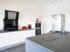 A modern kitchen with a built-in oven, a coffee maker, and a red toaster.