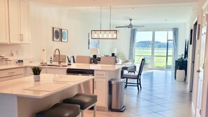 Een moderne keuken met een centraal eiland, barkrukken en een eethoek met uitzicht.