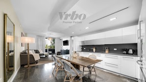 A modern kitchen with white cabinets, a dining table with chairs, and a large mirror.