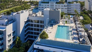 A high-rise hotel with a rooftop pool, surrounded by palm trees and ocean views.