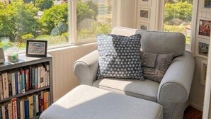 A cozy room with a grey sofa, a bookshelf, and framed pictures on the walls. - Charming, light-filled home - walk to the beach! (Aptos)