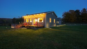 Une cabane en bois avec une véranda, un jacuzzi et des guirlandes lumineuses.