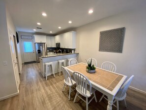 A modern kitchen with white cabinets, a central island, and bar stools. - Set Sail 7 - Spacious Townhome 3 Bed/2.5 bath/sleeps7 - 1 min walk to the beach! (Mexico beach)