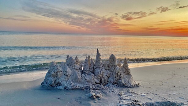 A sandy beach with a large sandcastle in the foreground. - Set Sail 7 - Spacious Townhome 3 Bed/2.5 bath/sleeps7 - 1 min walk to the beach! (Mexico beach)
