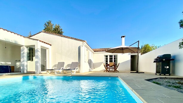 Une piscine avec des chaises longues et un barbecue.