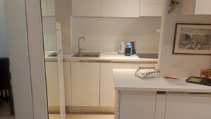 Una cocina moderna con armarios blancos, un lavamanos integrado y una cafetera en la encimera.