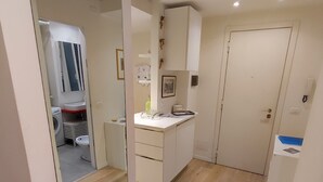 Una cocina moderna con armarios blancos, suelo de madera y un lavadero visible al fondo.
