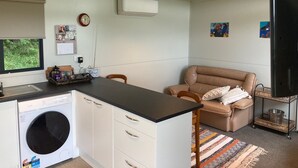 Eine kompakte Küche mit Waschmaschine, ein Essbereich mit braunem Ledersofa und einem Fernseher.