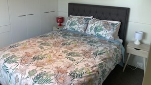 Ein Schlafzimmer mit Bett, Nachttisch, Kleiderschrank und einem Gemälde an der Wand.