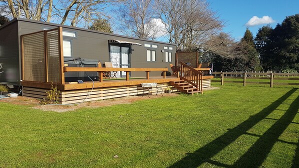 A modern mobile home with a deck, outdoor seating, and a small staircase leading to the entrance. - Country tiny house with spa (Arapuni)