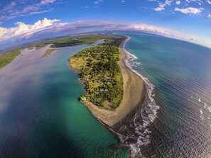 Eine Luftaufnahme einer Küsteninsel mit Strand, klarem Wasser und einer kleinen Siedlung.