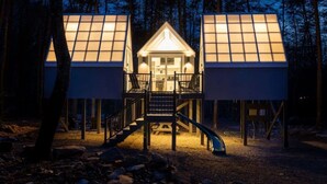 A cabin with a central entrance, two side wings, and a staircase leading to the main deck. - The Glo Haus @ Four Fillies Lodge (Peterstown)