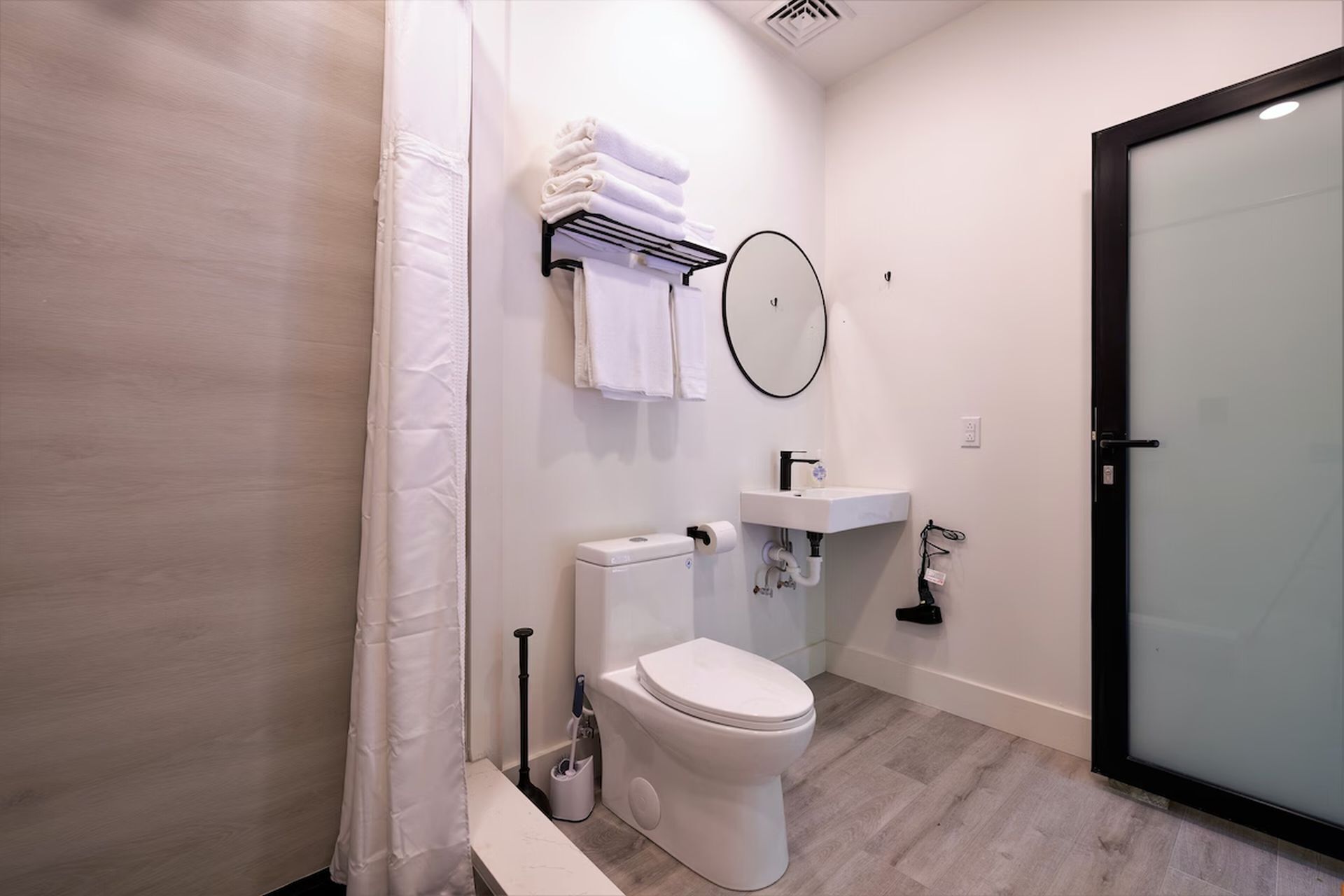 Een moderne badkamer met toilet, wastafel en handdoekrek.