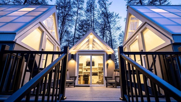 A cabin with a wooden deck, a glass door entrance, and a staircase leading to the door. - The Glo Haus @ Four Fillies Lodge (Peterstown)