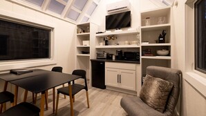 A compact kitchen with a dining area, a built-in TV, and a cozy seating arrangement. - The Glo Haus @ Four Fillies Lodge (Peterstown)