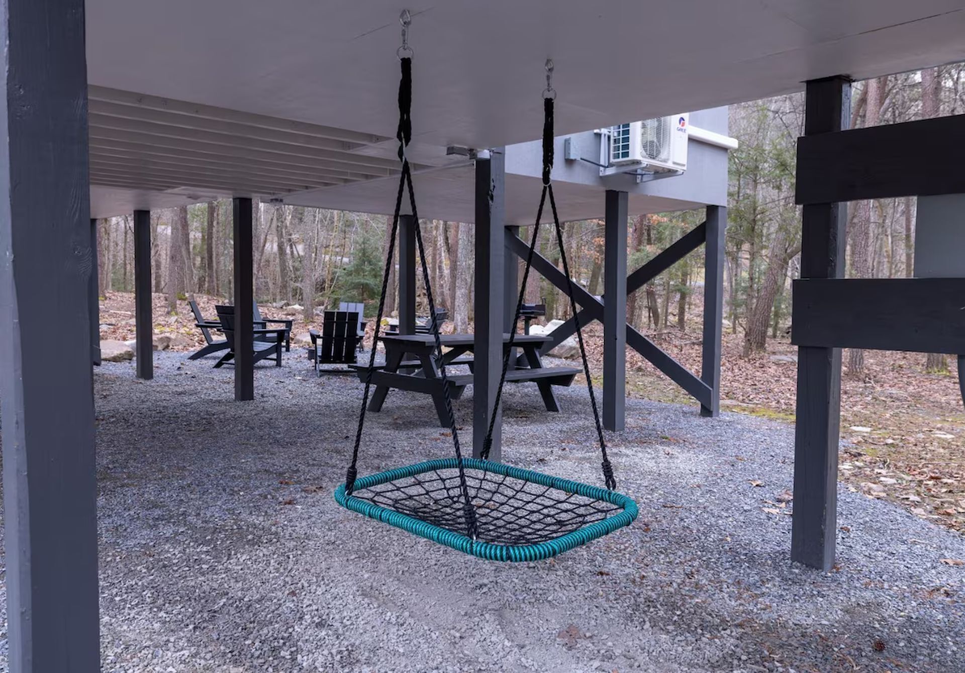 A covered outdoor area with a swing, picnic tables, and chairs.