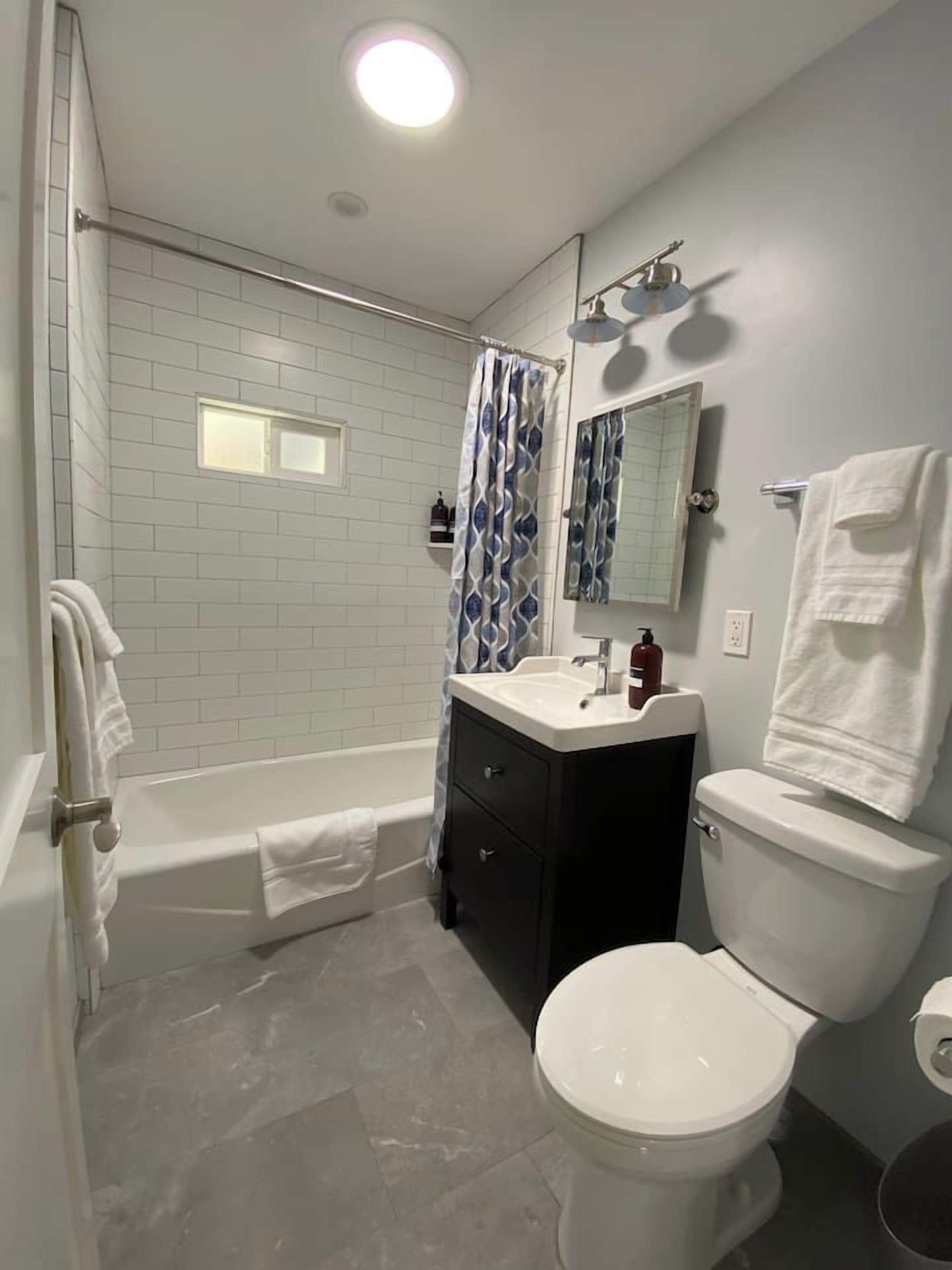 Ein Badezimmer mit Badewanne, Toilette, Waschbecken und Spiegel.