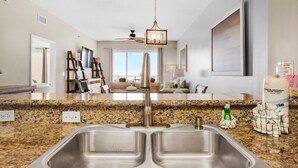 A modern kitchen with a double sink, granite countertop, and a ceiling fan.