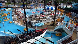 A large indoor water park with multiple swimming pools, inflatable rings, and a boat-shaped play area.