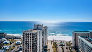 A high-rise hotel with multiple floors, a beach view, and a parking area.
