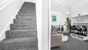 Eine Treppe führt zu einem Wohnbereich mit Fernseher, einer Couch und einem Couchtisch.