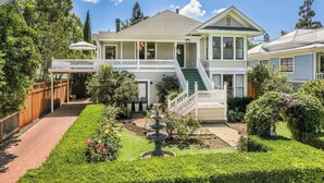 A two-story house with a front porch, a staircase, and a well-maintained garden with a fountain.