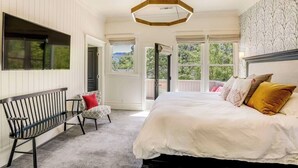 A bedroom with a large bed, a bench, and a view of the outdoors.