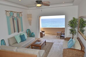 A spacious living area with a view of the ocean, a ceiling fan, and a large window. - Zuperb 3 Bedroom Ocean View Apart Isla Mujeres (Isla Mujeres)