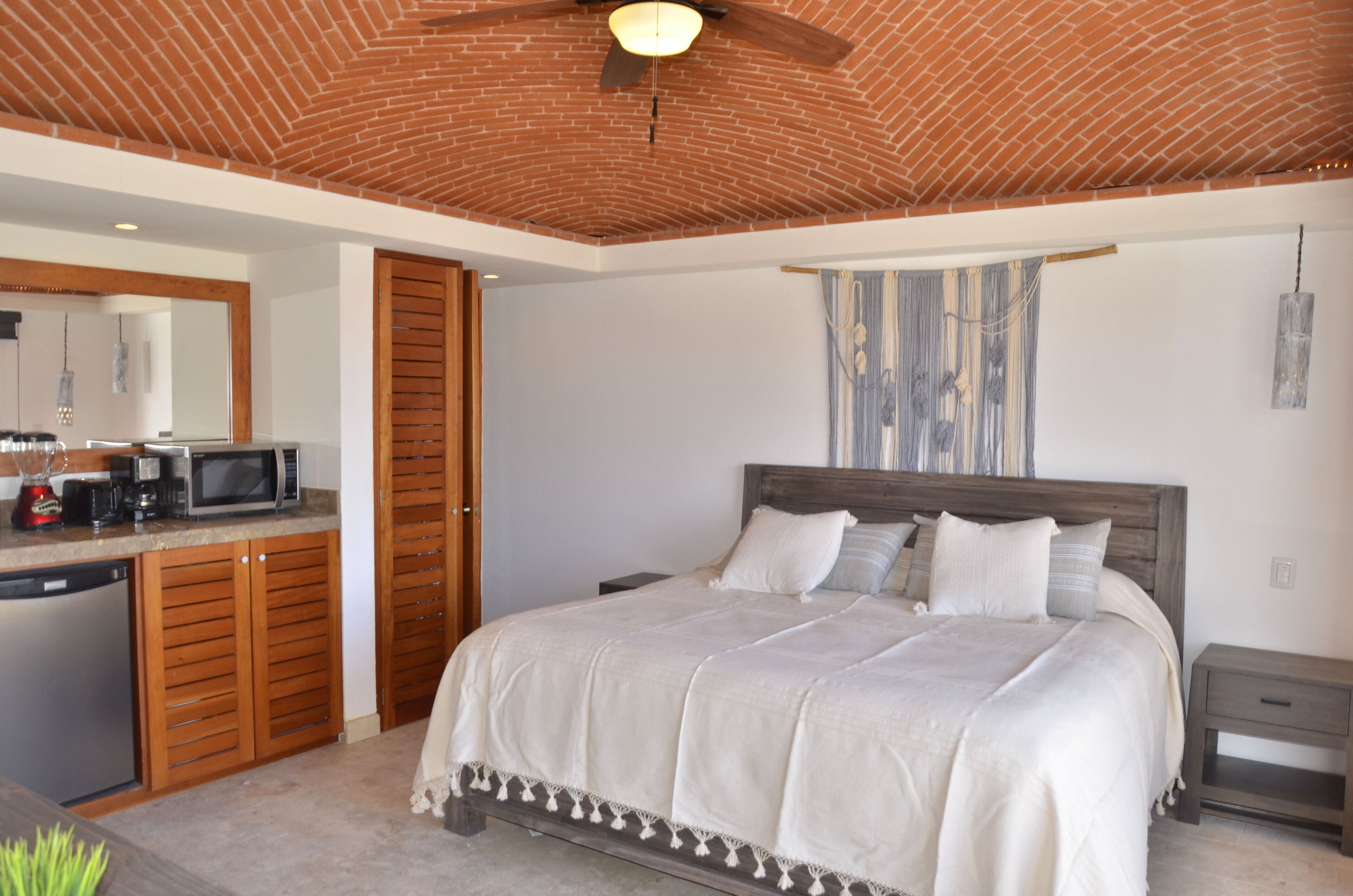 A bedroom with a large bed, wooden headboard, and a ceiling fan.