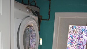 A laundry room with stacked washers and dryers, a tiled floor, and a door with a stained glass window. - Waterfront adjacent to the Gulf of Mexico (Hudson)