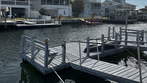A waterfront property with a dock, a covered area, and a building with a balcony. - Waterfront adjacent to the Gulf of Mexico (Hudson)