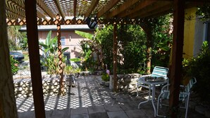 A covered patio area with a wooden pergola, stone seating, and potted plants. - Waterfront adjacent to the Gulf of Mexico (Hudson)