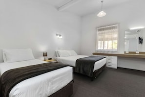 Habitación de hotel con dos camas, una mesita de noche con lámpara, un ventanal con cortinas, un espejo y una luz en el techo.