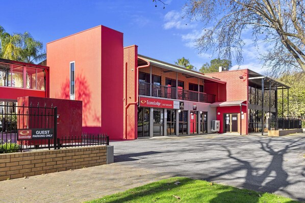 A red building with a guest parking sign, a covered walkway, and a sign for EconoLodge East Adelaide.