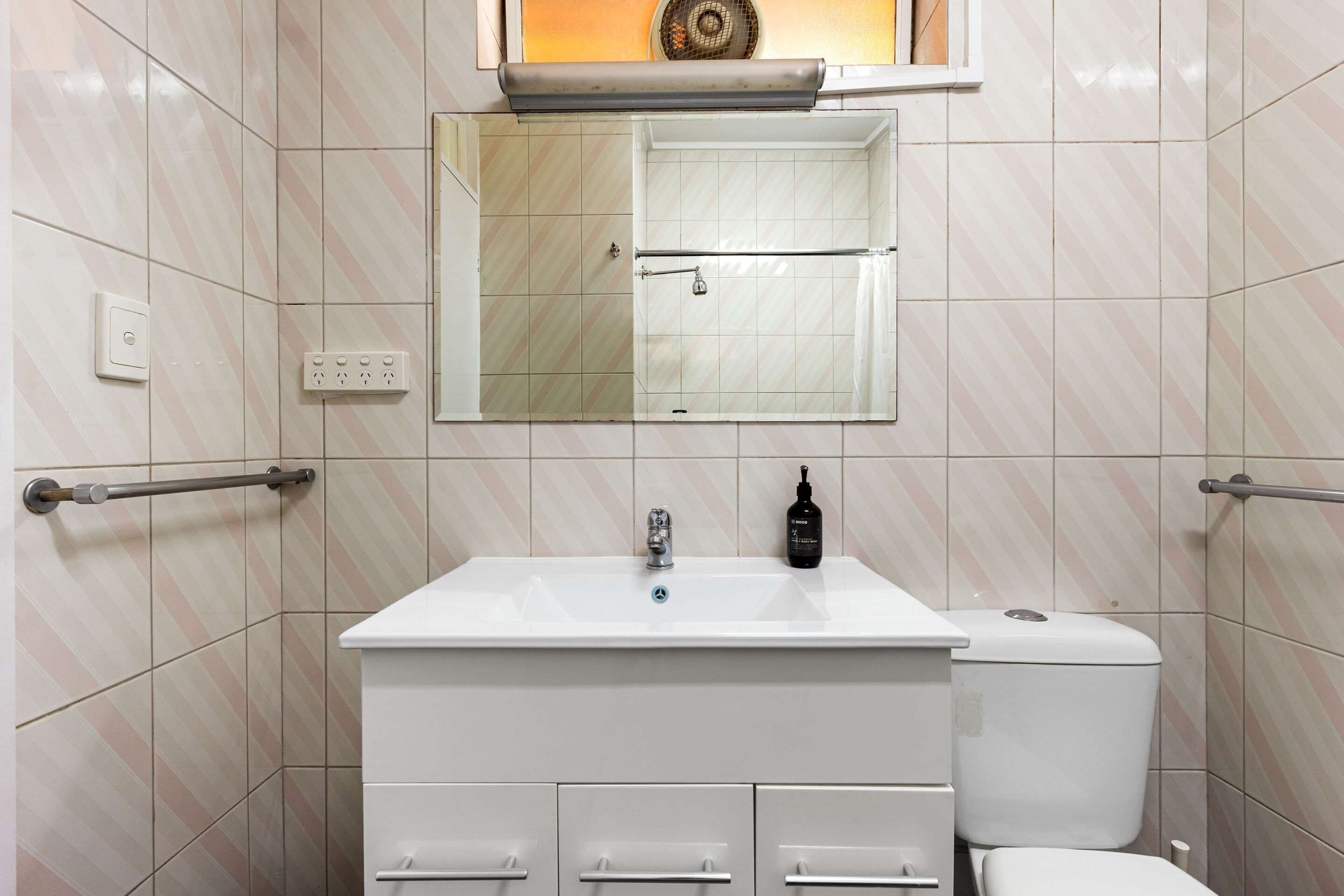 A bathroom with a white sink, a mirror, a toilet, and a towel rack.