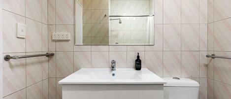 A bathroom with a white sink, a mirror, a toilet, and a towel rack.