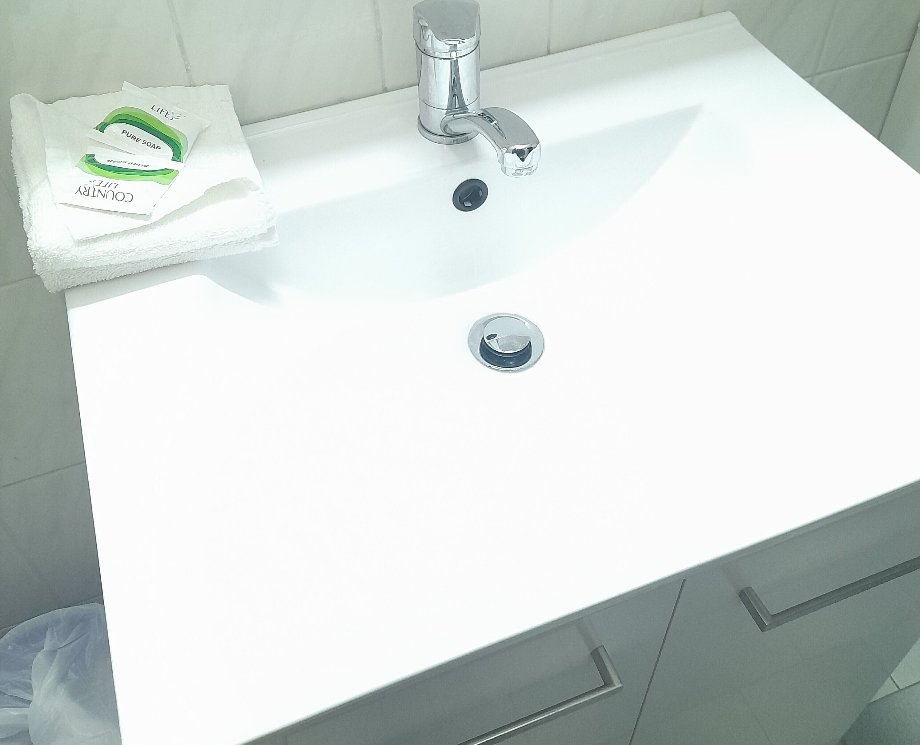 A white bathroom sink with a chrome faucet, a towel, and a soap dispenser on the counter.
