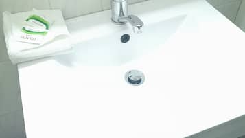 A white bathroom sink with a chrome faucet, a towel, and a soap dispenser on the counter.
