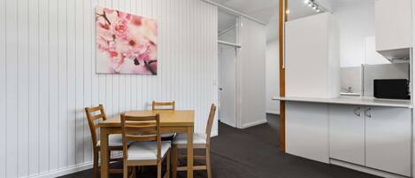 A modern kitchen with white cabinets, a dining table with chairs, and a wall-mounted picture of flowers.