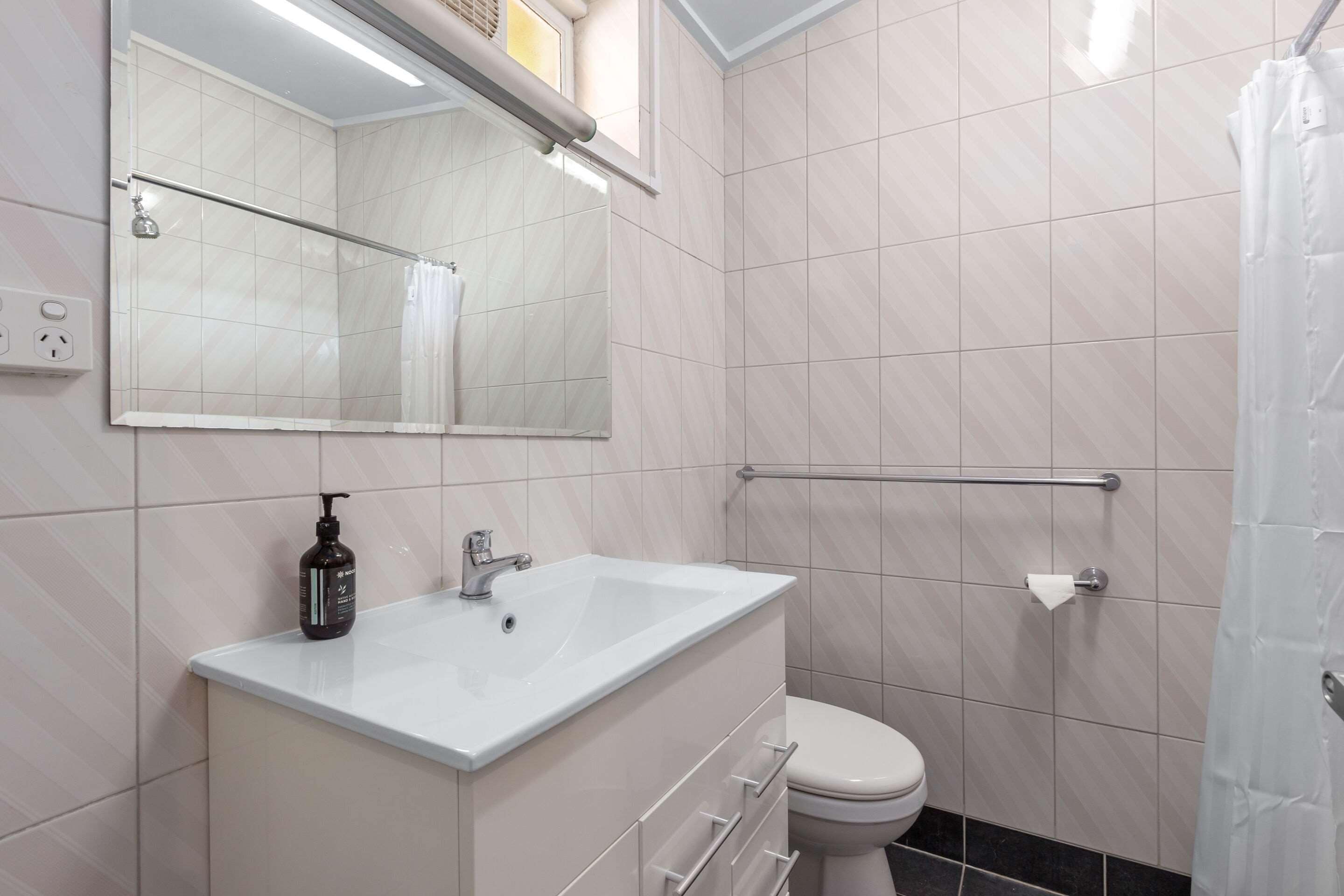 A modern bathroom with a white sink, mirror, and toilet.