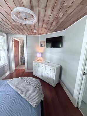 A bedroom with a bed, a dresser, a lamp, and a television on the wall. - Old Town Key West Cottage 3bed/2bath (Key West)