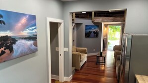 A hallway with a stone floor, a painting of a beach scene, a sofa, and a refrigerator. - Old Town Key West Cottage 3bed/2bath (Key West)