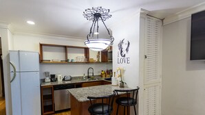 A compact kitchen with a refrigerator, stove, sink, and bar stools. - Ocean View Central Location Modern Studio (Montego Bay)