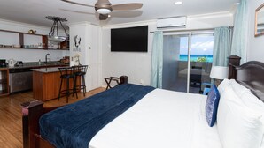 A hotel room with a bed, a desk with a chair, a TV, and a balcony with a view. - Ocean View Central Location Modern Studio (Montego Bay)