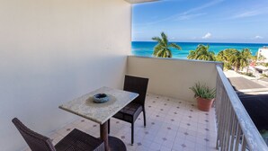 A balcony with a table and chairs, a potted plant, and a view of the ocean. - Ocean View Central Location Modern Studio (Montego Bay)