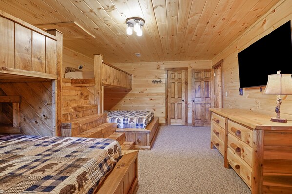 Een chalet met twee houten bedden, een kapstok en een trap naar een deur.