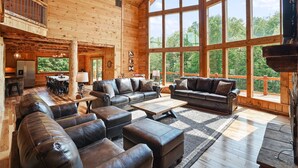 Ein großzügiger Wohnbereich mit Ledersofas, einem Couchtisch und großen Fenstern mit Blick ins Freie.