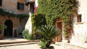 A stone building with a courtyard, potted plants, and a wooden door. - Petit Hotel Son Perdiu Agroturismo (Llucmajor)