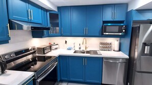 A modern kitchen with blue cabinets, stainless steel appliances, and a microwave. - Adorable 2 bedrooms, 2 washrooms, 2 parking spots apartment (Newmarket)