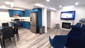 A modern kitchen with blue cabinets, a stainless steel refrigerator, and a dining area with black chairs. - Adorable 2 bedrooms, 2 washrooms, 2 parking spots apartment (Newmarket)